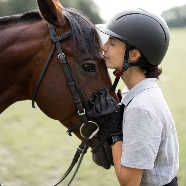 Female horseman hugging head of Thoroughbred horse